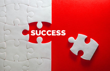 Close up piece of white jigsaw puzzle with SUCCESS text , a concept of business challenge success completion with teamwork - obrazy, fototapety, plakaty