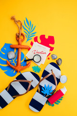 Traveling essentials flat lay on a vibrant yellow background. Summer vacation accessories, sunglasses, flip-flops, sunscreen, Vacation note on a calendar, wooden anchor with blue and pink palette.