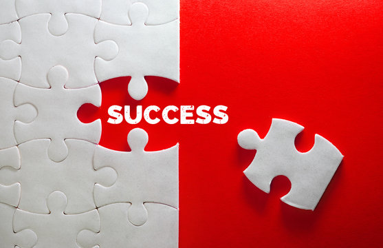 Close up piece of white jigsaw puzzle with SUCCESS text , a concept of business challenge success completion with teamwork
