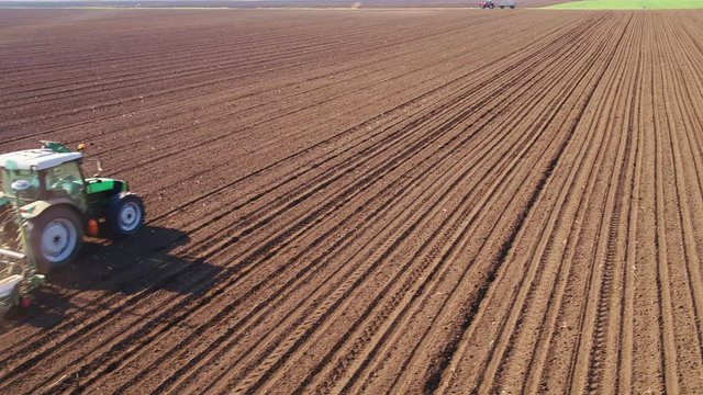 Aerial shot of a farmer seeding, sowing crops at field.