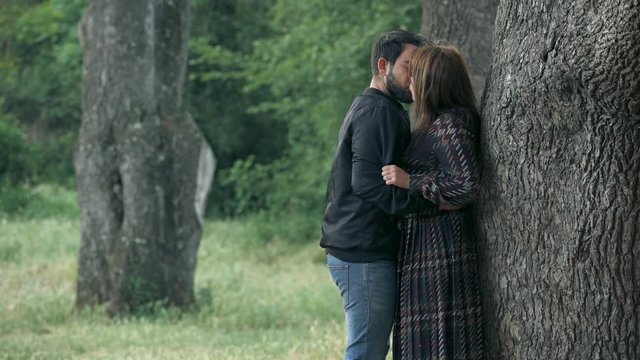 jealousy scene- young lovers kissing under a tree in the park ex violent boyfriend arriving