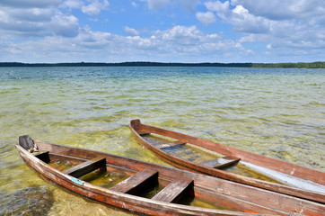 Obraz premium Old wooden fishing boats on the lake beach with blue sky.