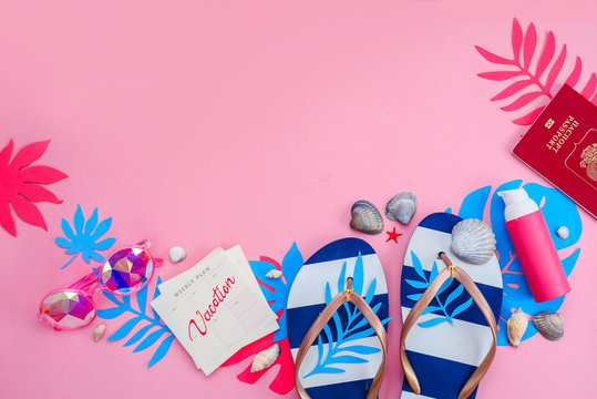 Header with flip flops, sunglasses and sunscreen on a vibrant pink background with copy space. Feminine summer vacation essentials concept. Colorful travel flat lay with tropical leaves.