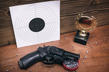 Obraz premium Best shooter award background with copy space. Winner in shooting. Gun, paper target and gold medal. Shooting range.