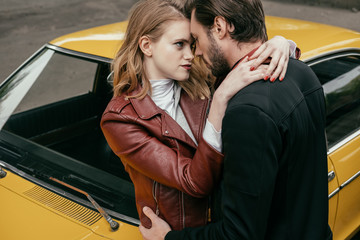beautiful sensual young couple hugging near yellow old-fashioned car