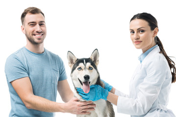smiling young man with husky and female veterinarian isolated on white background