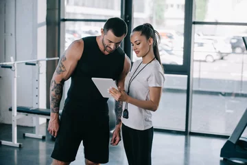  female personal trainer and sportsman looking at screen of digital tablet at gym © LIGHTFIELD STUDIOS
