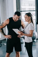 female personal trainer and sportsman looking at screen of digital tablet at gym © LIGHTFIELD STUDIOS