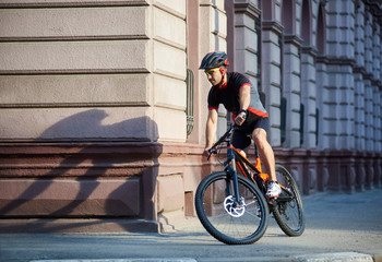 Obraz premium Bicyclist in professional cycling clothing and protective helmet riding bicycle along old historical city streets, taking turns, performing tricks in urban area