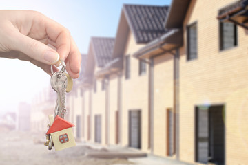 Real estate agent handing a house key, Key with a key chain in the shape of house on new home background. Mortgage concept