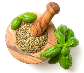 dried herb, basil leaves in the wooden mortar, isolated on white, top view
