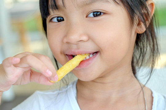 Cute Asian Girl Happy Eating French Fries.