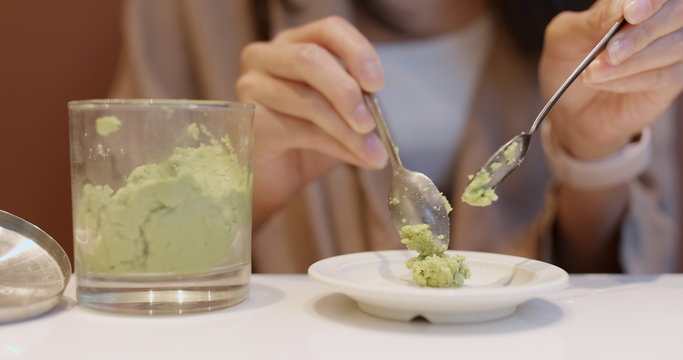 Woman putting wasabi on plate in Japanese restaurant