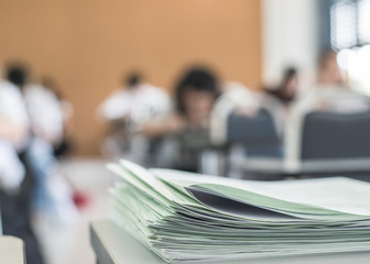 Exam answer sheet or application paper blurry view on table in examination room with blur education background of school university students taking exam test writing answer in seat row with stress
