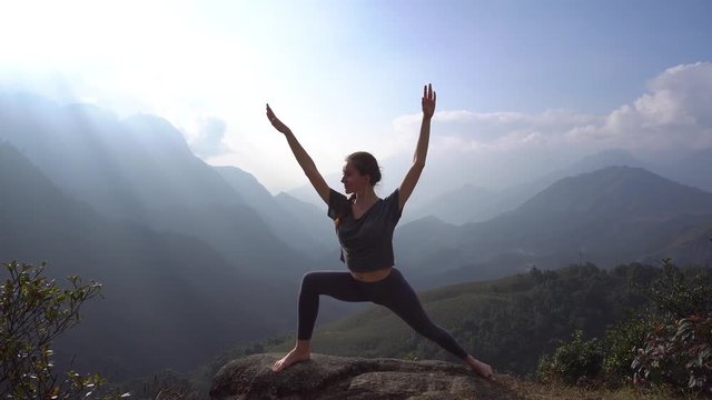 Yoga. Woman exercising and warming up on mountain cliff
