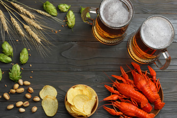 Glass beer with crawfish, hop cones and wheat ears on dark wooden background. Beer brewery concept....