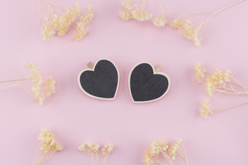 Two heart shape board decorate with white dried flowers on pastel pink background