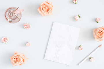 Feminine workspace with notebook, rose flowers, marble paper blank. Flat lay, top view, copy space