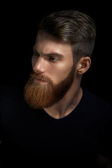 Portrait of young bearded man isolated at black background Guy with beard thoughtful, pensive, charming, looking forward