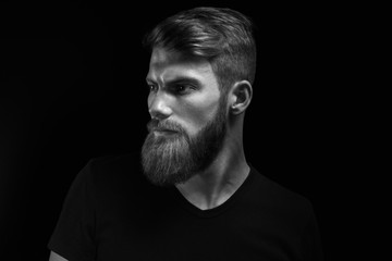 Black and white studio shot of confidence attractive hipster Dramatic light concept Black background Copy space Bearded man