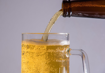 Beer in a glass poured from a bottle thrown from the ice and foam