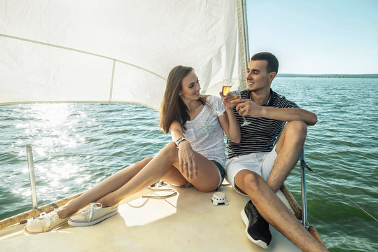 Romantic couple in love on sail boat drinking wine under sunset