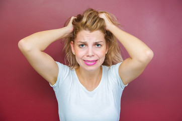 Fototapeta premium Concept of worry, woman with both hands on head on red background.