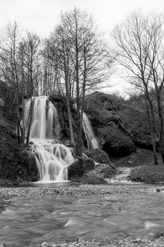 Beautiful Serbian waterfall long time exposure photography, water motion in black and white. Winter image with river in front