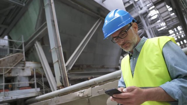 Industrial engineer standing in recycling plant using phone