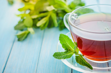 Mint tea in a glass cup on a wooden background