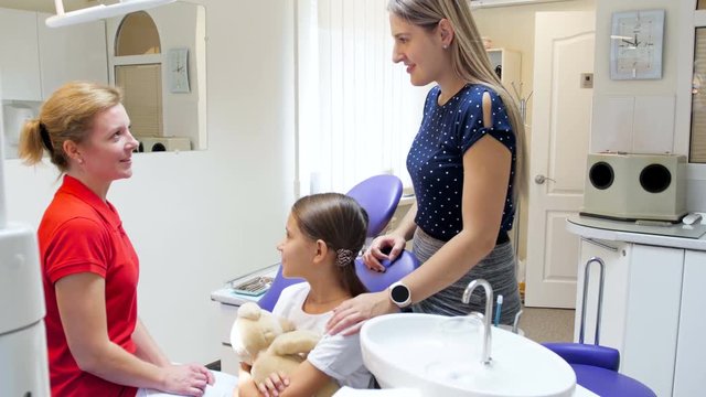 4k footage of young mother with teenage girl talking to dentist in dental clinic