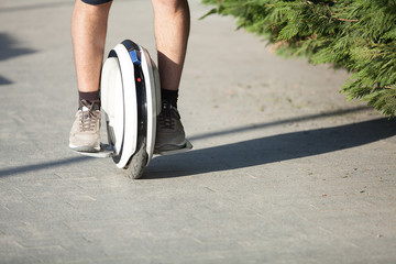  The young man is riding on a white stylish monocle. Legs.