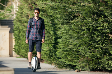 A stylish guy moves along the sidewalk on a mono-wheel.