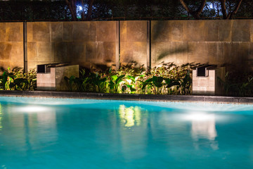 Fototapeta na wymiar Lush pool lighting in backyard for luxury swimming pool design created by great lighting professionals.