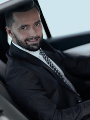 Confident businessman with laptop sitting in auto.