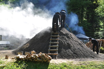 Köhler arbeitet am traditionellen Holzkohlemeiler zu Herstellung von Holzkohle aus Buchenholz