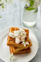 delicious Viennese waffles with ice creamon saucer in spring composition on wooden background