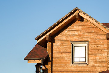 Part of modern wooden country house with blue sky on background. Roof of eco residential building near forest. Building and architecture of rustic chalet