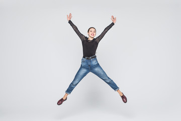 happiness, freedom, power, motion and people concept - smiling young woman jumping in air with raised fists over white background