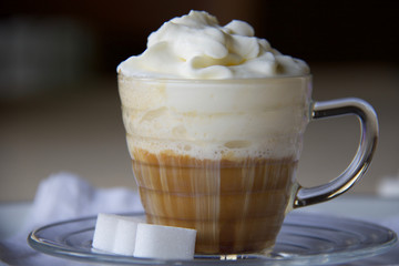 close up of trasparent glass cup of coffee with whipped cream