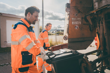 Garbage man and women cleaning dustbins into waste truck cleaning the street