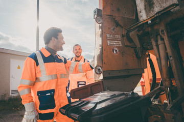 Two garbagemen working together on emptying dustbins for trash removal