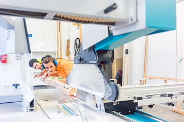 Man and woman carpenter cutting board working together
