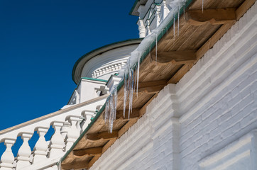 Garland of icicles, hanging down from roof of an ancient white stone fortress wall and towers looks...