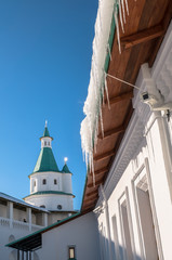 Garland of icicles, hanging down from roof of an ancient white stone fortress wall and towers looks...