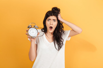 Shocked excited woman holding alarm clock looking camera.