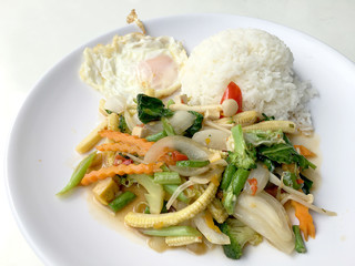 Stir mix vegetables  with gravy sauce and thai style fried egg in white plate on white background. Vegetarian Food, healthy food.