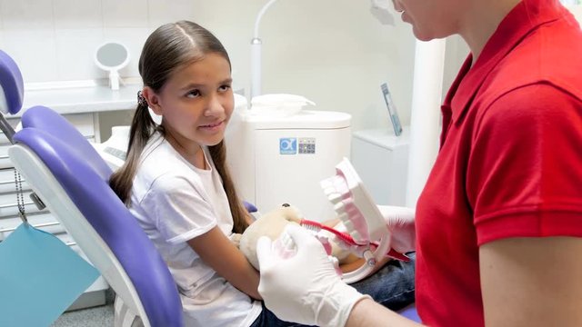 4k closeup video of dentist teaching teenage girl how clean teeth with toothbrush
