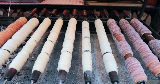Hungarian cinnamon chimney cake sweet dessert being cooked grilled prepared on the street