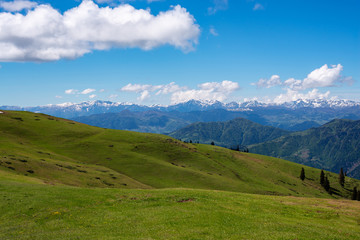 Fototapeta na wymiar Green mountain slopes stretch under blue sky